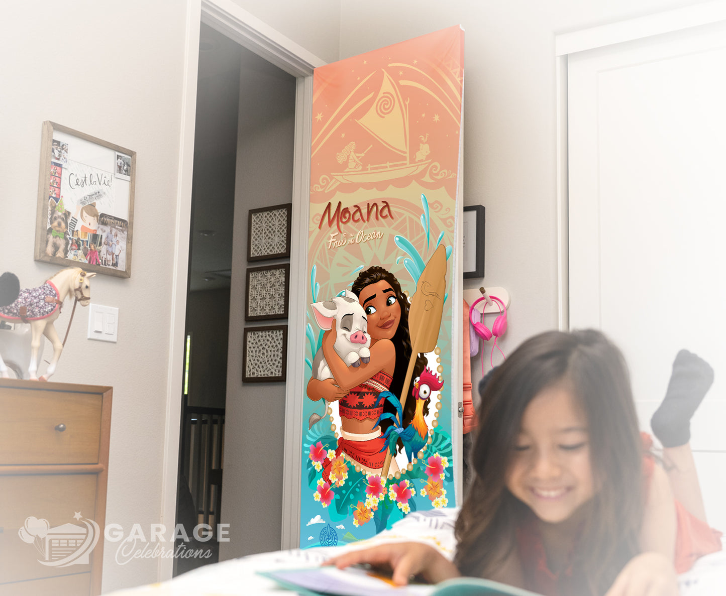Child reading a book in front of a decorative Moana door cover in a room.