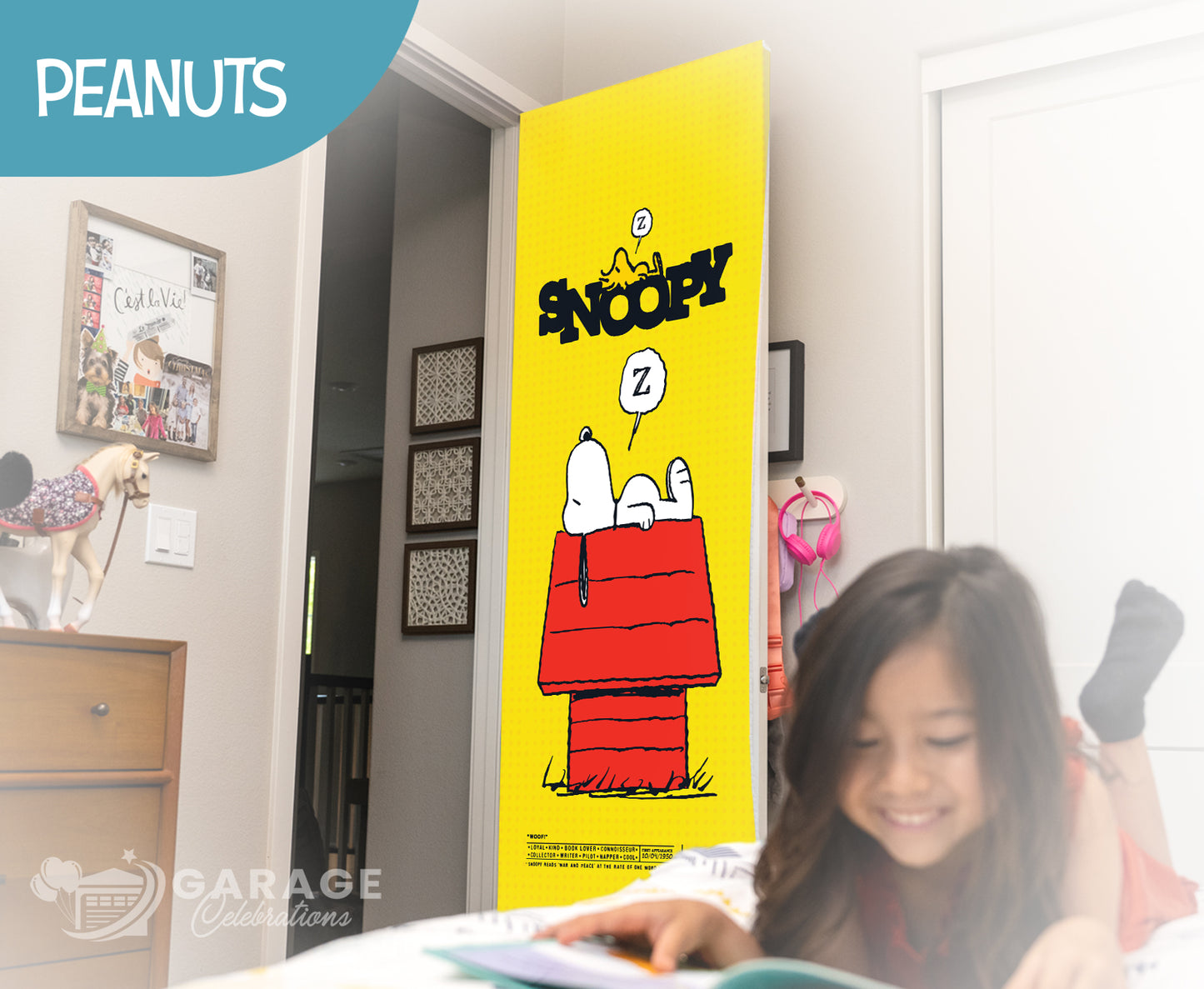 Girl reading a book in front of a Snoopy door cover in a room with 'Peanuts' branding.